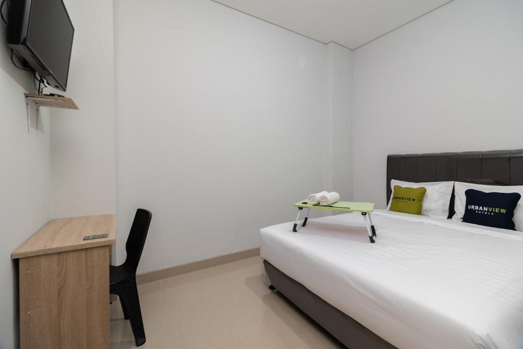 a bedroom with a bed with a tv and a table at Urbanview Hotel Pasar Baru Jakarta by RedDoorz in Jakarta