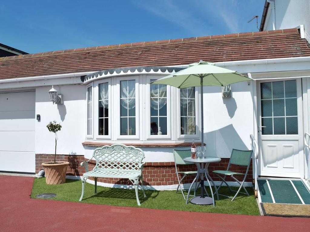 Casa blanca con mesa y sombrilla en The Annexe en Clacton-on-Sea