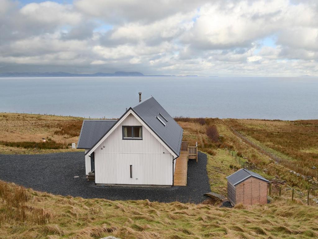 a white house on a hill next to the water at Fionn Croft Lodge in Aultgrishin