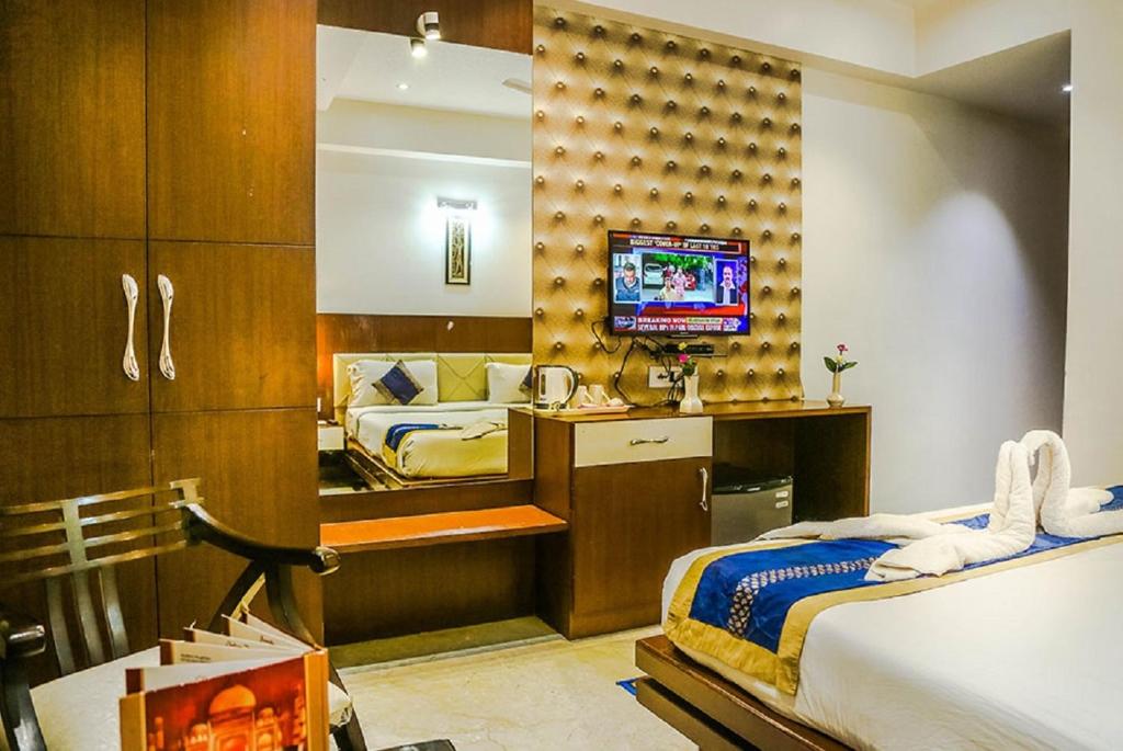 Hotel Taj Heights في آغْرا: غرفة نوم بسريرين وتلفزيون في غرفة