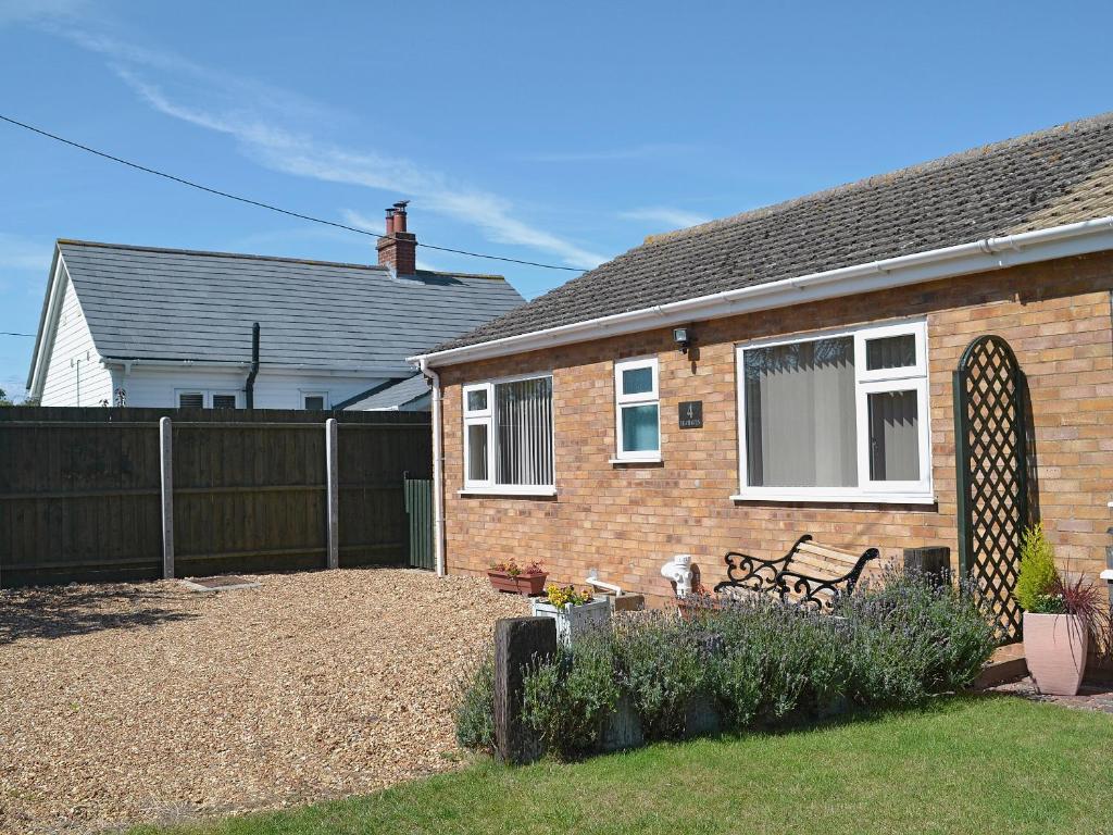 a brick house with a fence and a bench in a yard at Sea Haven in Heacham