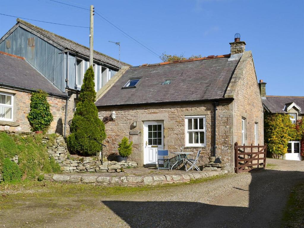 an old stone house with a fence in front of it at Felbridge Cottage in Bardon Mill