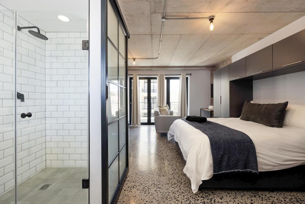 1 dormitorio con 1 cama y ducha acristalada en Manhattan On Coral Apartments en Bloubergstrand