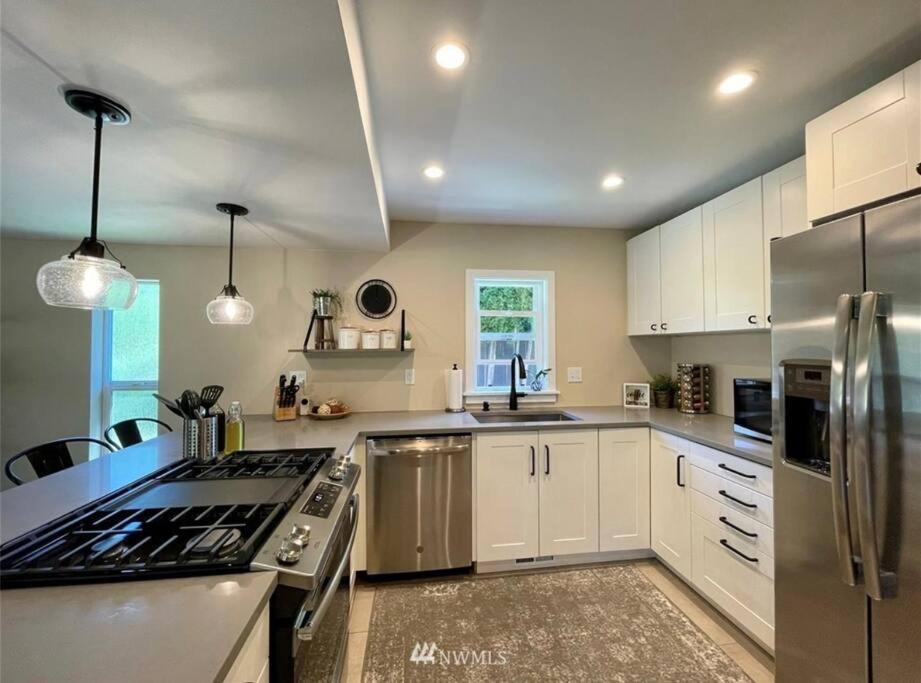 a kitchen with white cabinets and stainless steel appliances at Livable D near Lake Washington in Lake Forest Park
