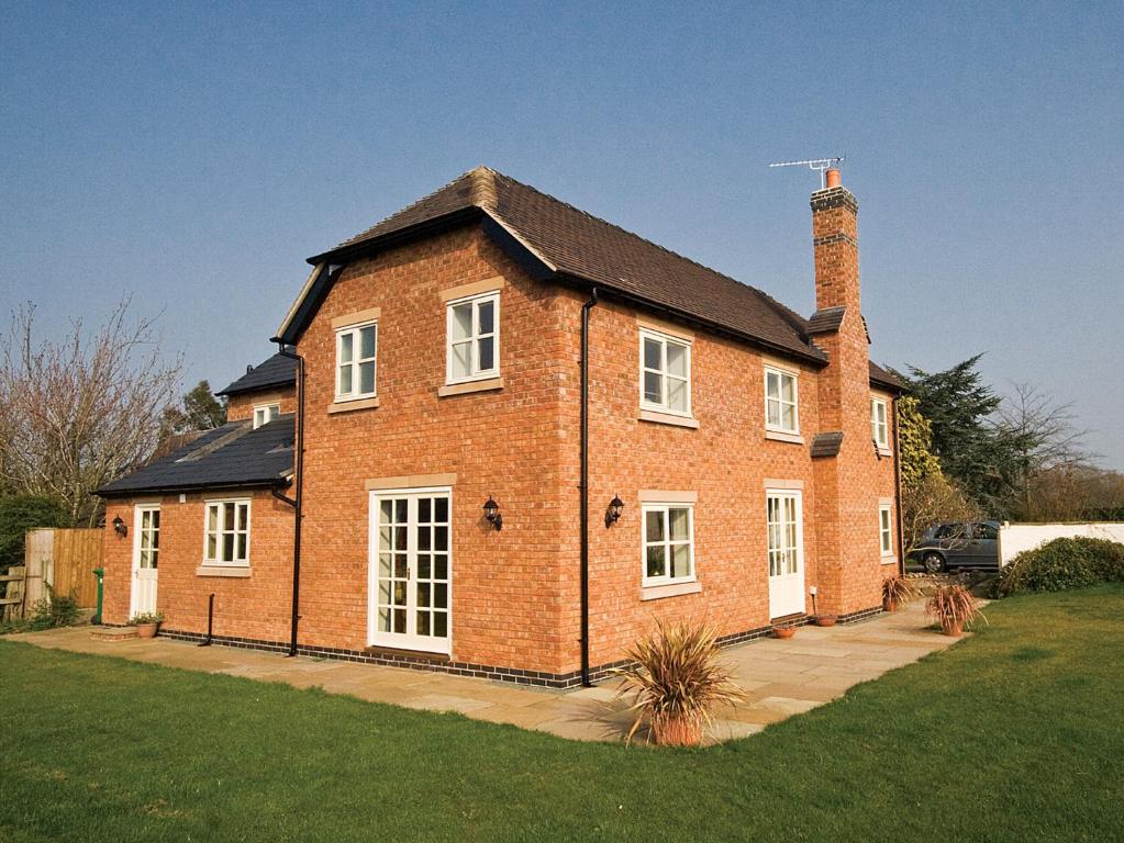 a large brick house with a chimney on top at Brook House Farm Cottage in Church Minshull