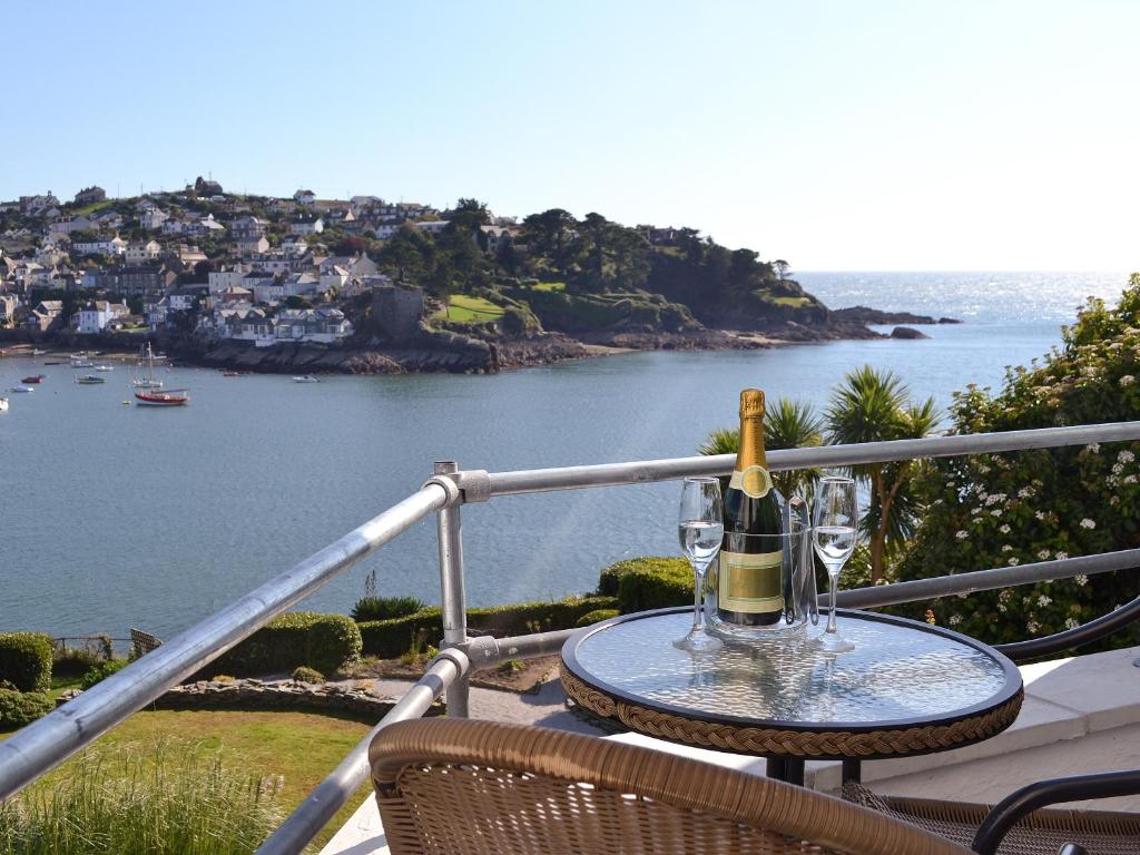 a table with a bottle of wine and glasses on a balcony at Waterside in Fowey