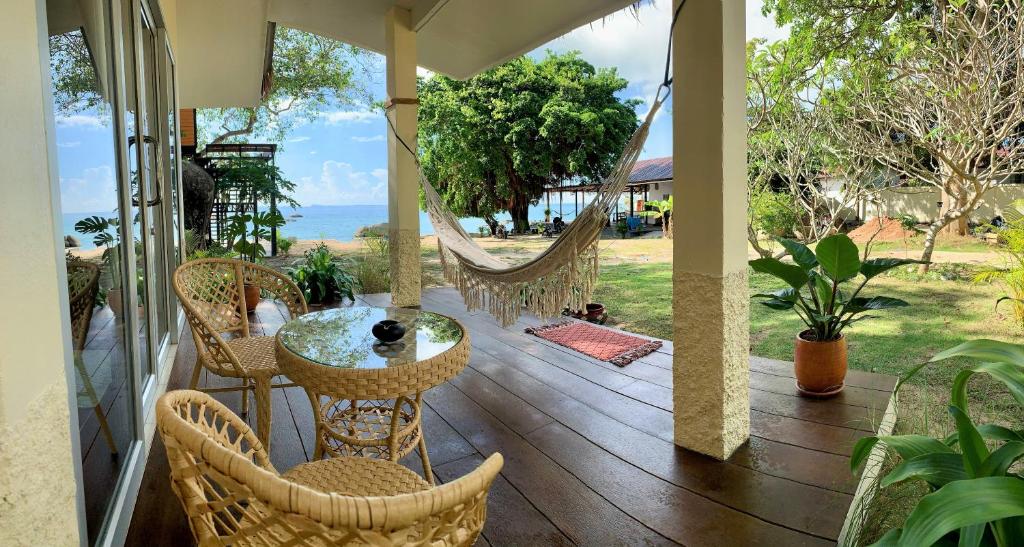 a porch with a hammock and a table and chairs at Ocean Vibes in Thong Sala