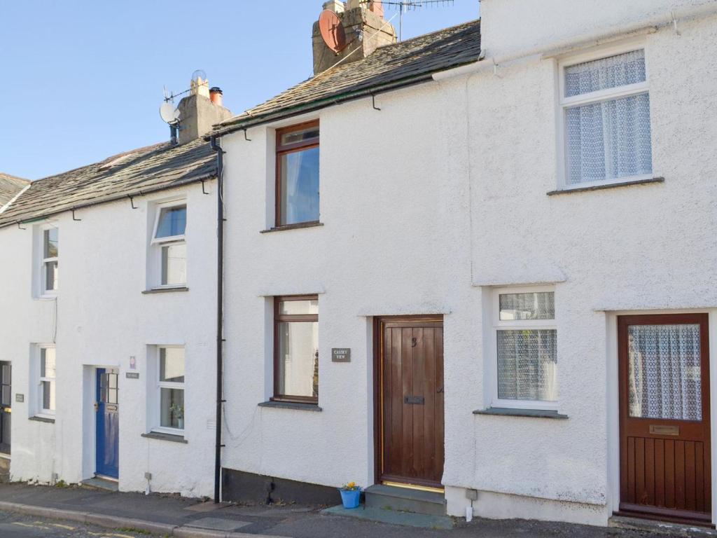 una fila de casas blancas con puertas de madera en Causey View, en Keswick