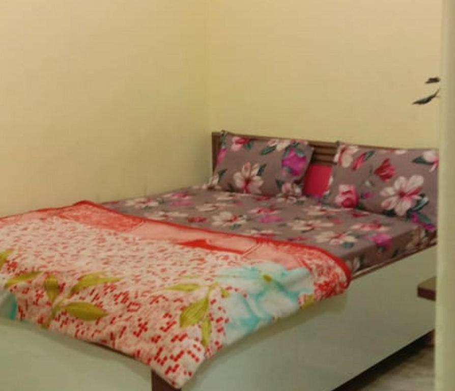a small bed with a floral bedspread and pillows at Hotel A Star & Restaurant By WB Inn in Ghaziabad