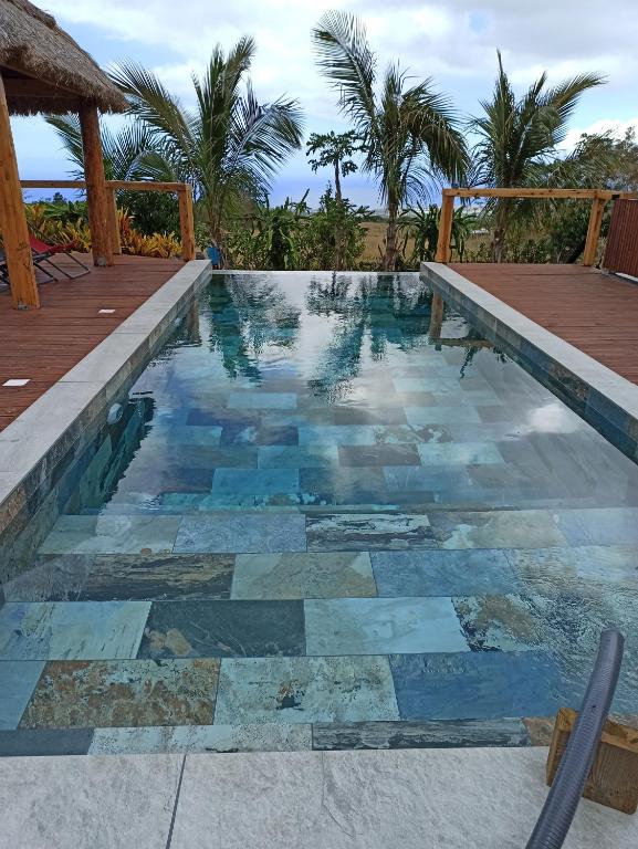 una piscina con suelo de baldosa y una terraza de madera en Gites de la falaise, en Le Tampon