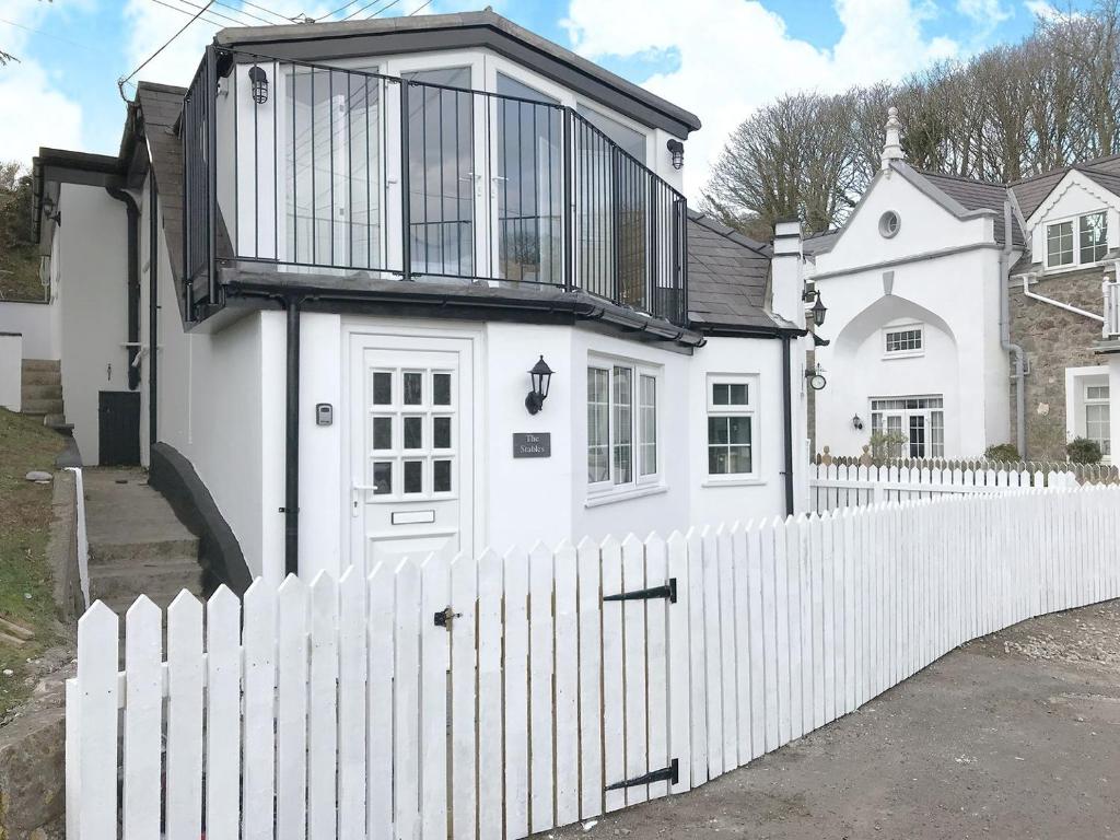 a white house with a white picket fence at The Stables in Penally