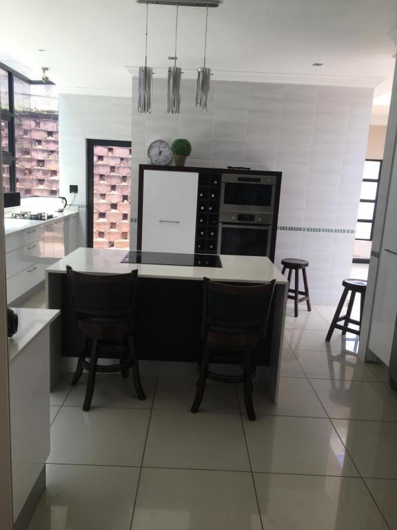 een keuken met een kookeiland met stoelen en een fornuis bij Durban luxury accommodation in Pinetown