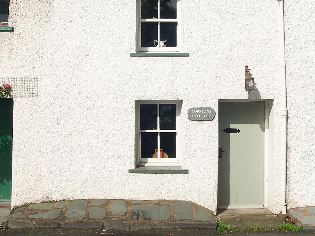 a white building with a door and a window at Lobstone Cottage in Rosthwaite