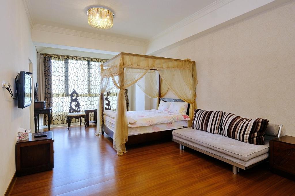 a bedroom with a canopy bed and a couch at Qixingtan Hai Wan B&amp;B in Dahan