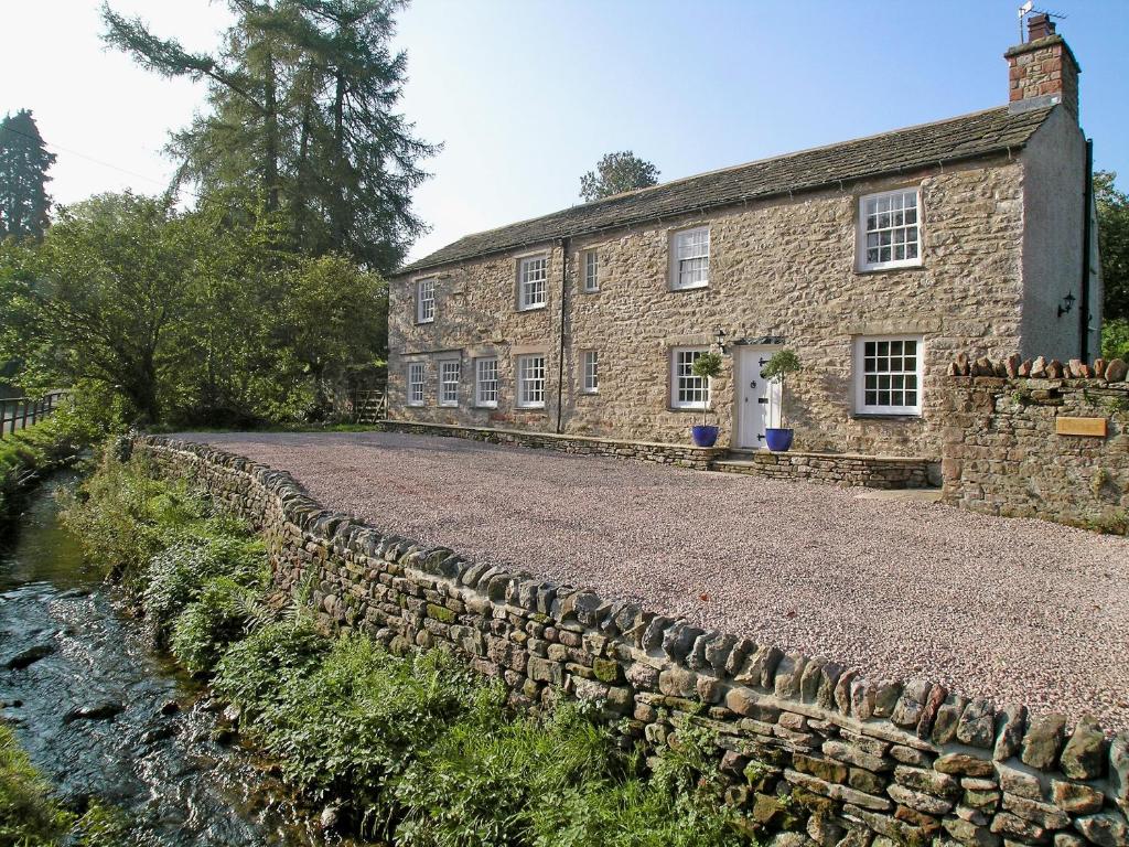 an old stone building next to a stone wall at The Larches in Kirkby Stephen