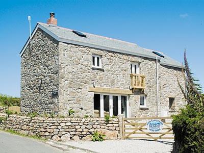 a stone house with a wooden fence in front of it at Porth Nanven Barn in St Just