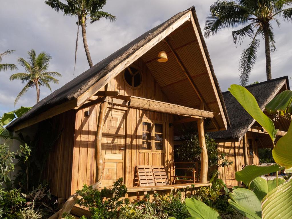 een houten huis met een veranda en palmbomen bij Camanolo Homestay in General Luna
