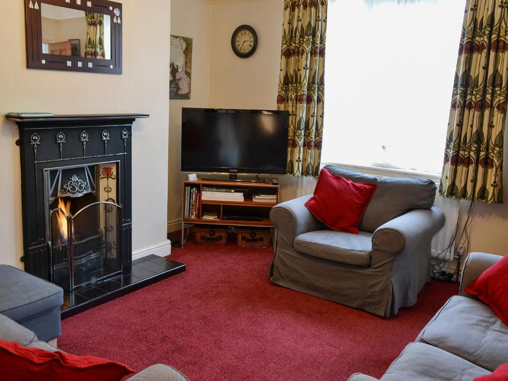 a living room with a fireplace and a television at Low Fold Cottage in Stainforth