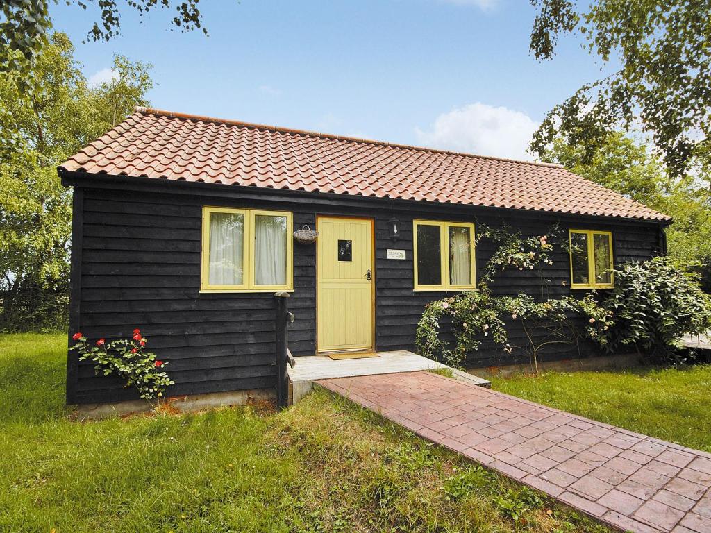 een klein zwart huis met een gele deur bij Briar Cottage - E5335 in Redisham