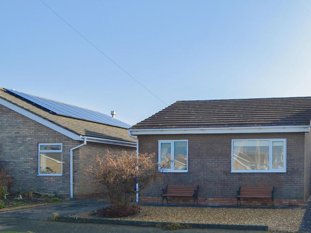 a brick house with two benches in front of it at 61 Longstone Close in Beadnell