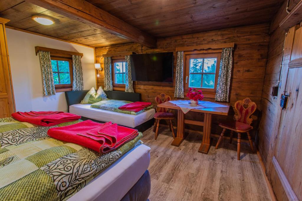 a room with two beds and a table in a cabin at Holzerjuwel - Minzlhof Ramsau am Dachstein in Ramsau am Dachstein