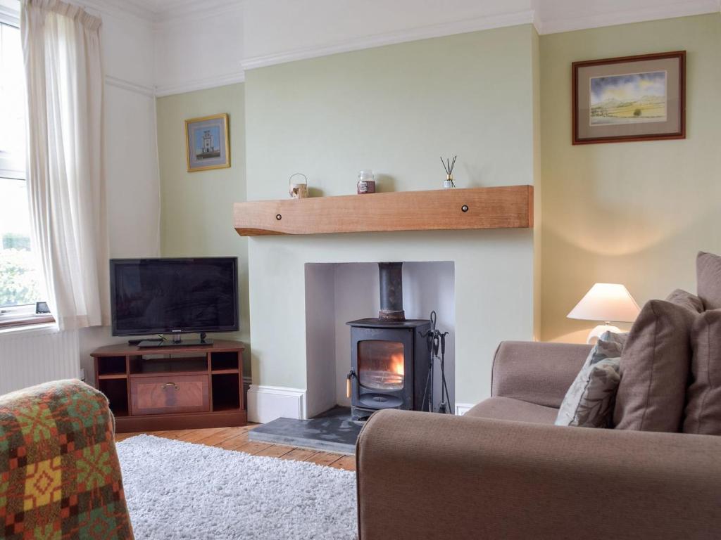 sala de estar con chimenea, sofá y TV en Middleton Cottage en Llanddarog