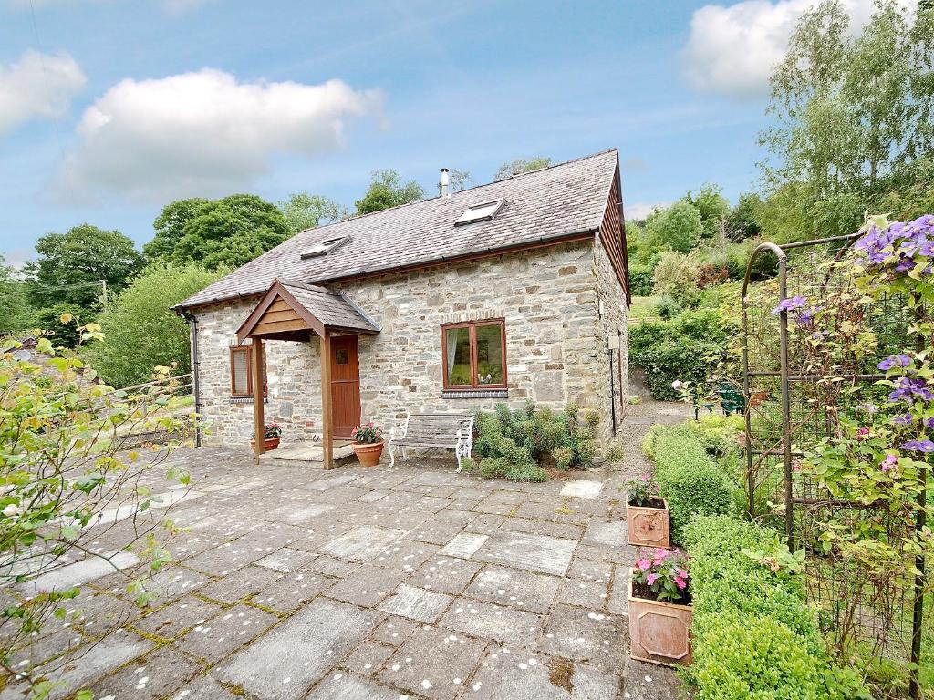 a stone house with a patio in a garden at Hope Cottage in Knighton