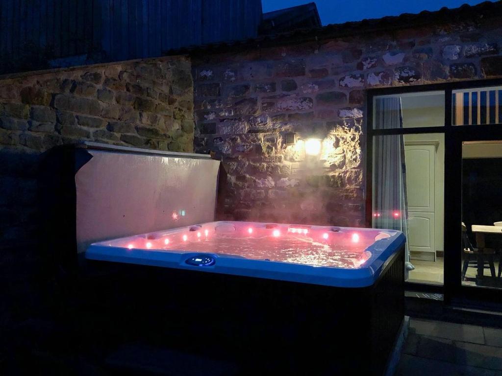 uma banheira de hidromassagem com luzes num quarto escuro em The Dairy em Beck Hole