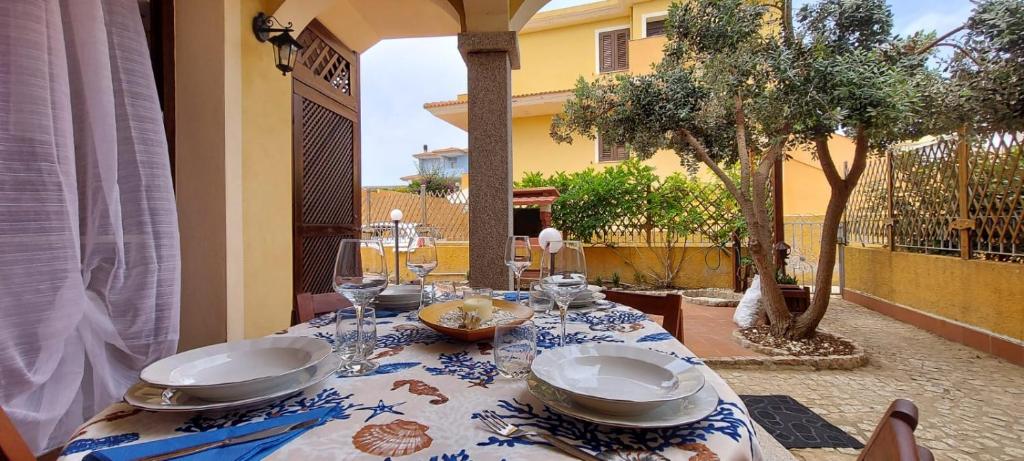 una mesa con platos y vasos encima en Casa giardino e barbecue en Castelsardo