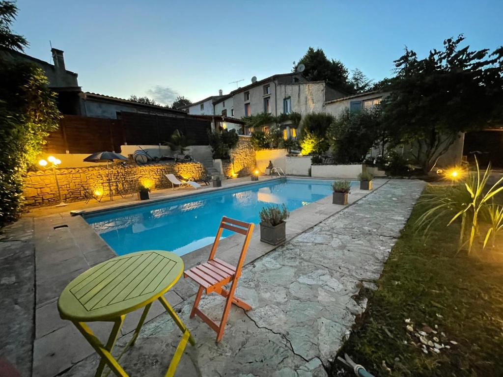 una mesa y sillas junto a una piscina en L'Ancienne Forge en Villarzel-du-Razès