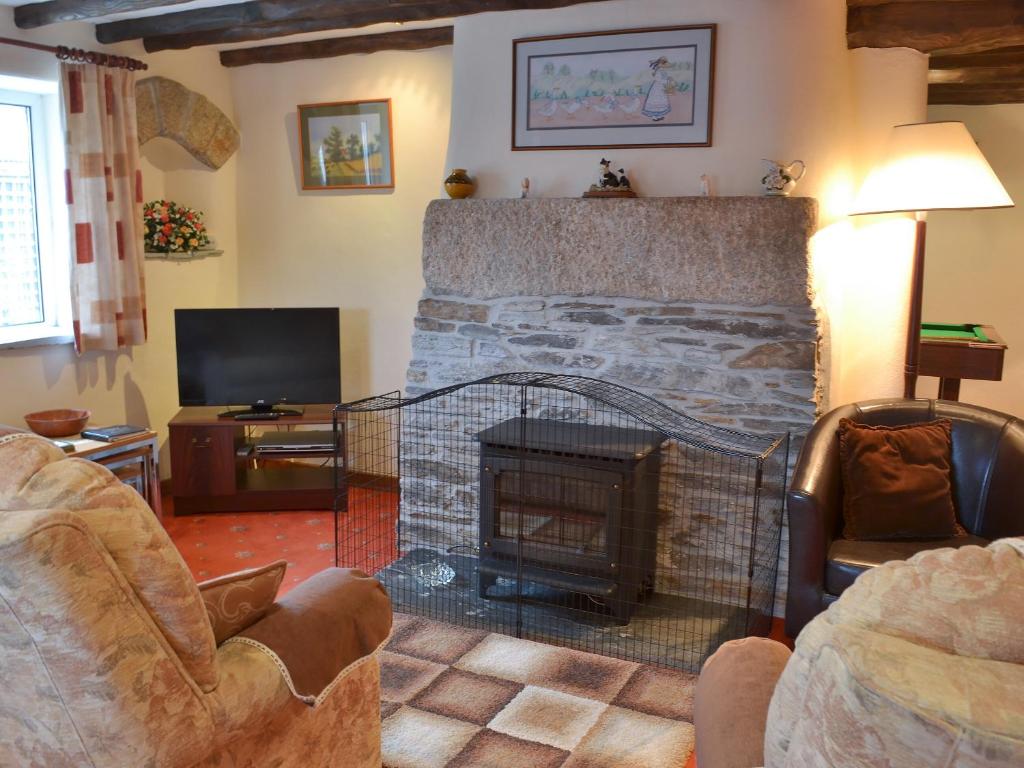 a living room with a stone fireplace and a television at Haycombe Cottage in Camelford