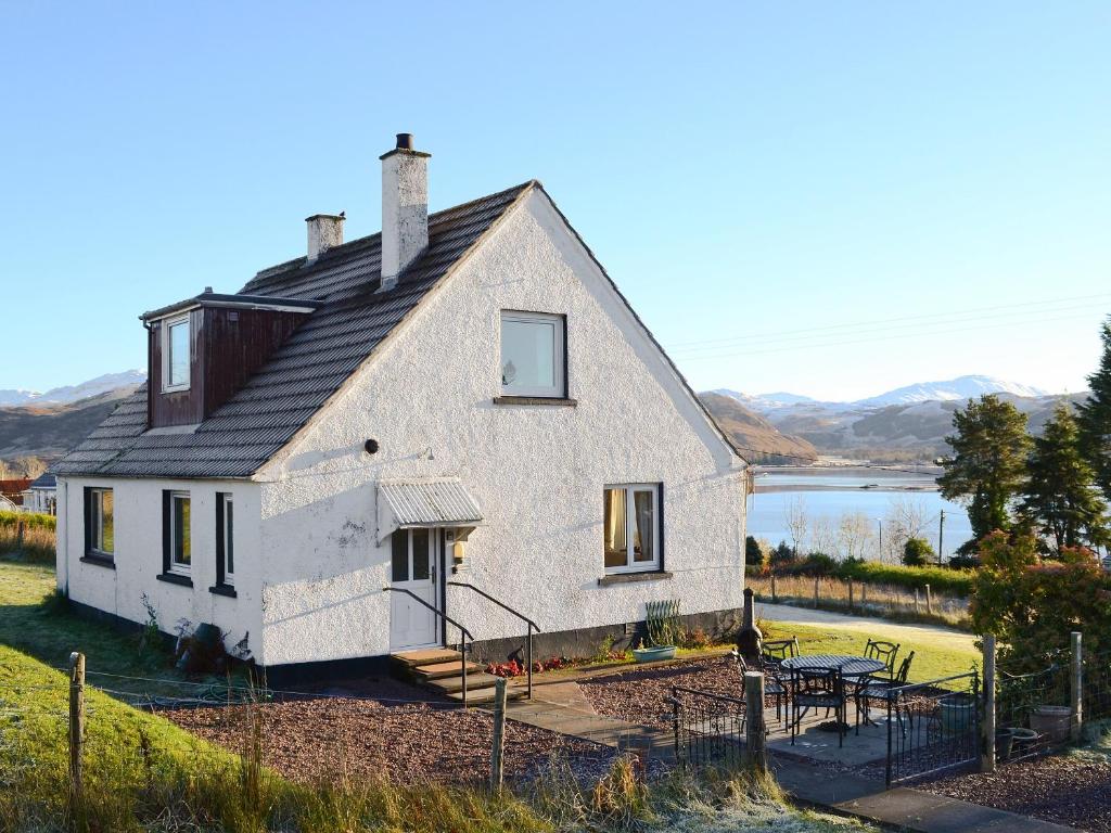 a large white house on a hill with a table at Druim-nan-deur in Lochcarron