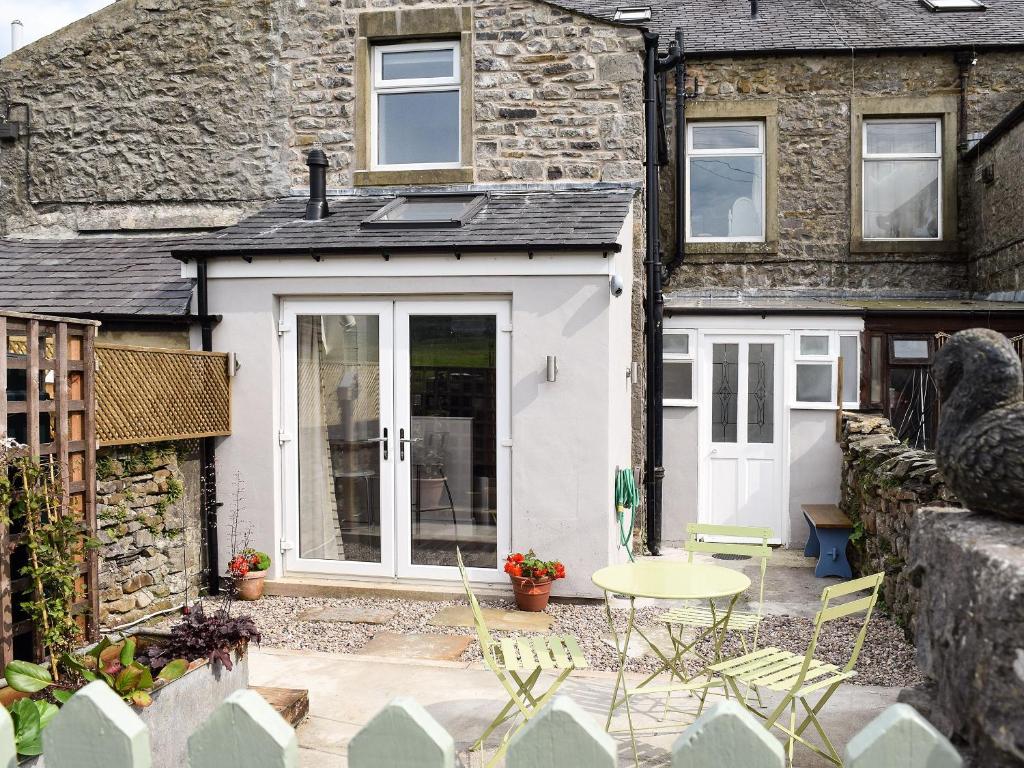a patio with a table and chairs in front of a building at Three Peaks House in Horton in Ribblesdale
