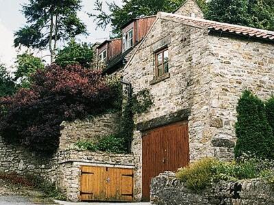 una antigua casa de piedra con dos puertas de garaje en Holly Cottage en Richmond