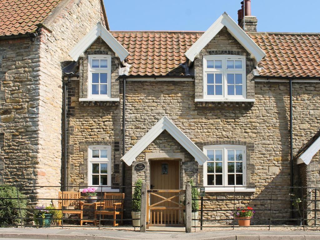 a brick house with white windows and a wooden door at Pond View Cottage in Brantingham