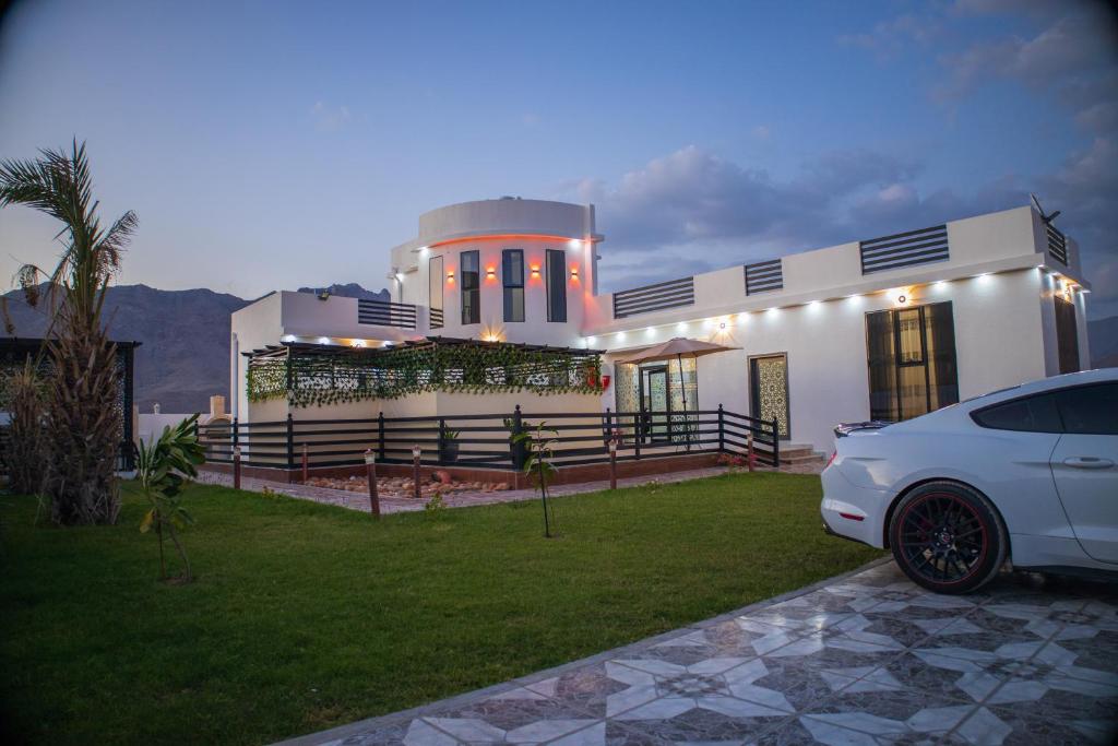 Highness Villa Nizwa في نزوى‎: سيارة بيضاء متوقفة أمام منزل