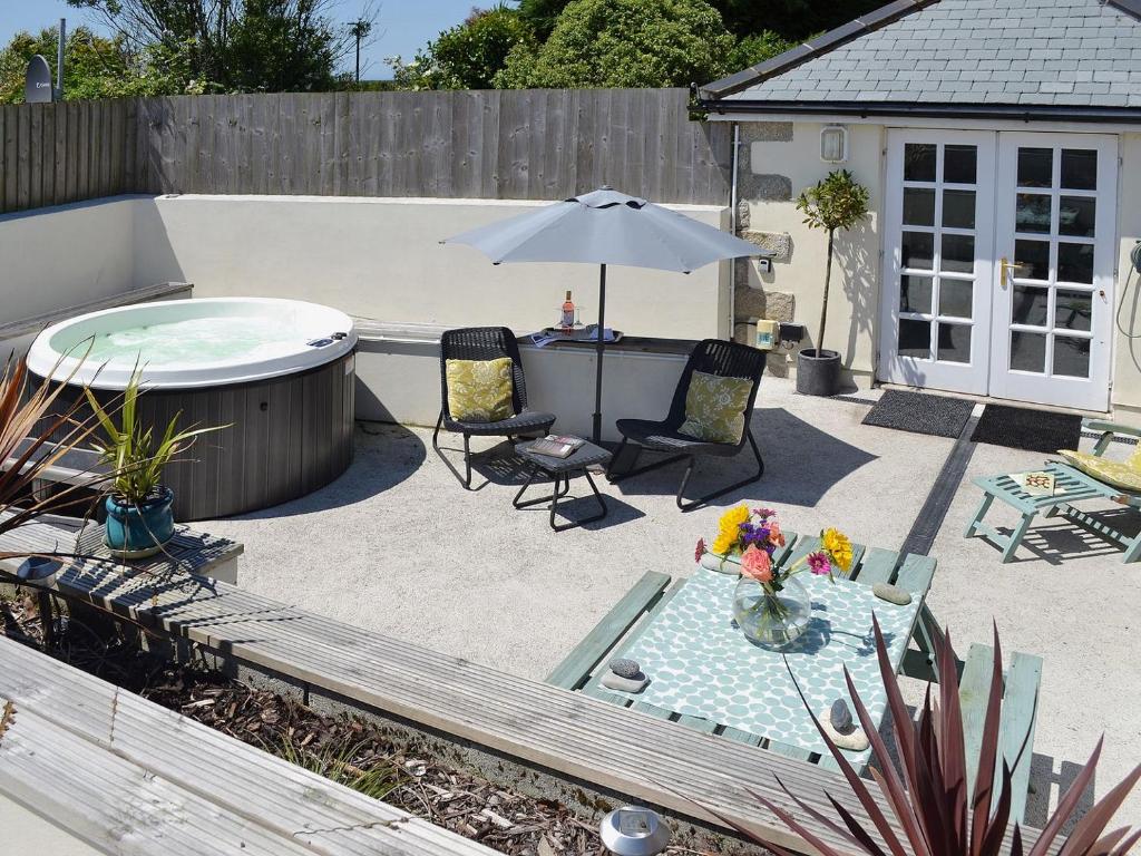 eine Terrasse mit einer Badewanne, Stühlen und einem Sonnenschirm in der Unterkunft Bowji in St Just