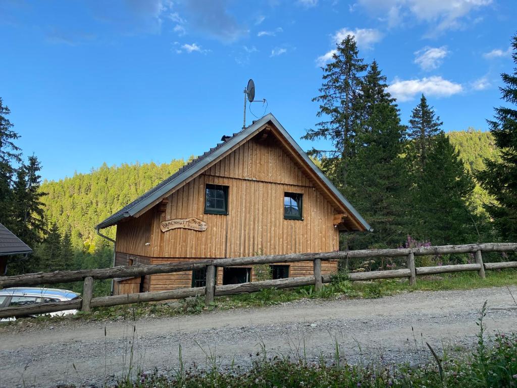 eine Holzhütte mit einem Zaun an einer Straße in der Unterkunft Bärenhütte in Turracher Hohe