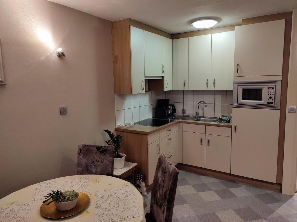 a kitchen with white cabinets and a table and a table and chairs at Your Stay in Kelmis - La Calamine- Cosy apartment in the Ardennes -Three-country point in Kelmis