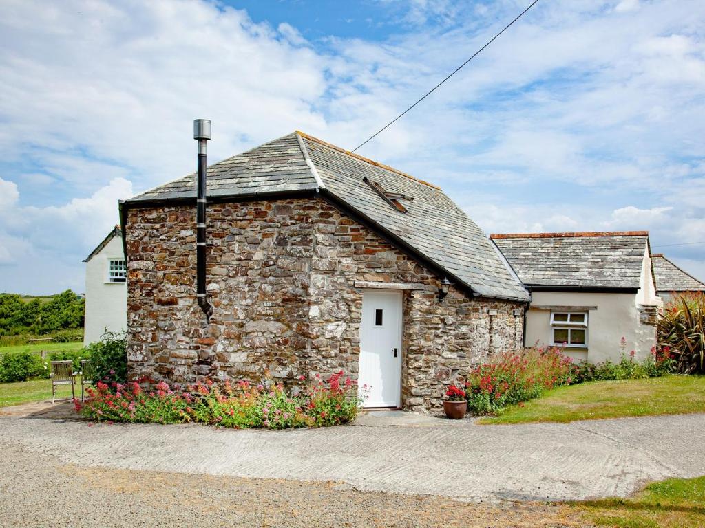 a small stone building with a white door at The Roundhouse - Tbe in Crackington Haven