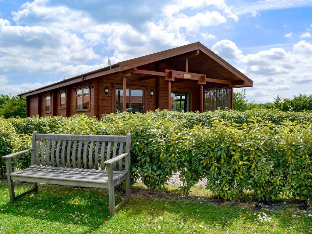 a wooden house with a bench in front of it at Bulrush Lodge in Burgh le Marsh