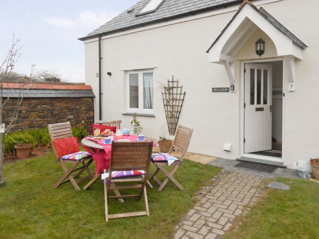 einen Tisch und Stühle vor einem weißen Haus in der Unterkunft Bellagio in Padstow