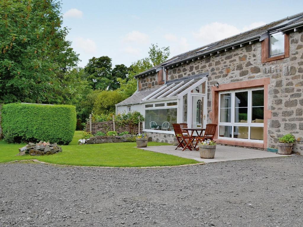 a stone house with a table and chairs in a yard at Rathlin Coach House in Comrie