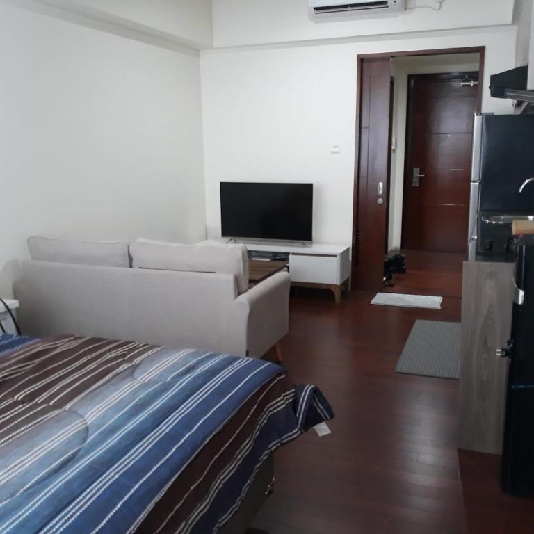 a living room with a bed and a television at The Accent Apartemen in Jurangmanggu