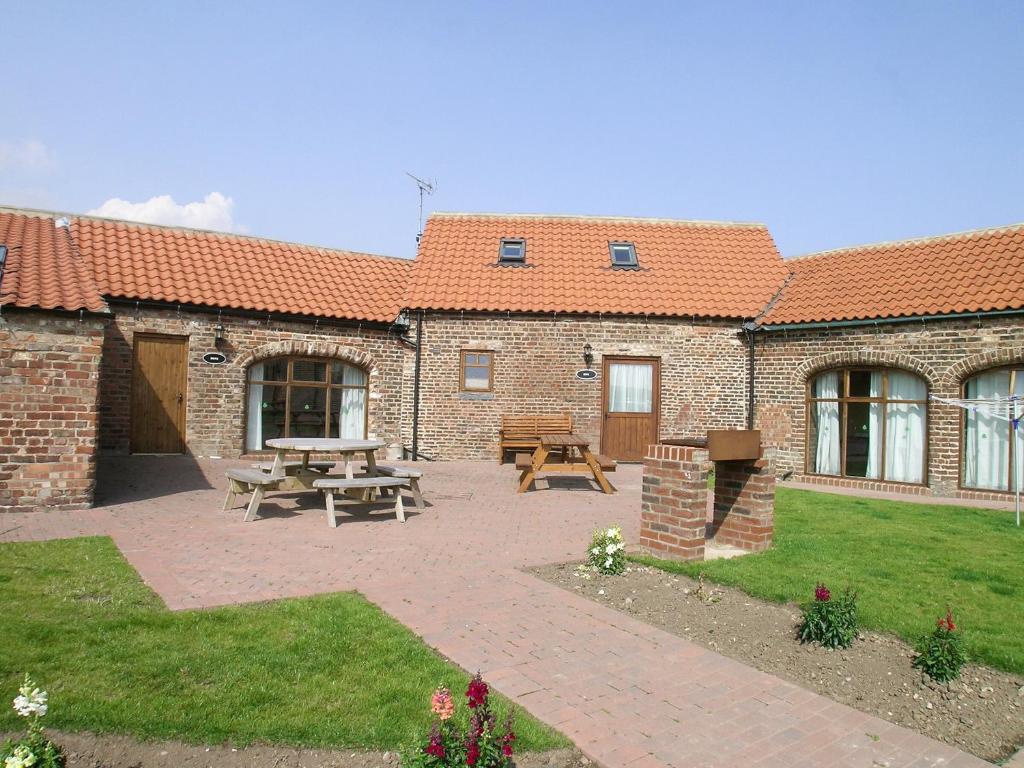 a brick building with a patio with a picnic table at Dove Cottage - 25117 in Flamborough