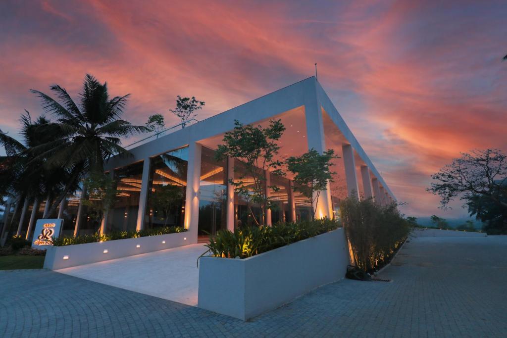 un edificio con una palmera frente a una puesta de sol en Grand Silver Ray en Ratnapura