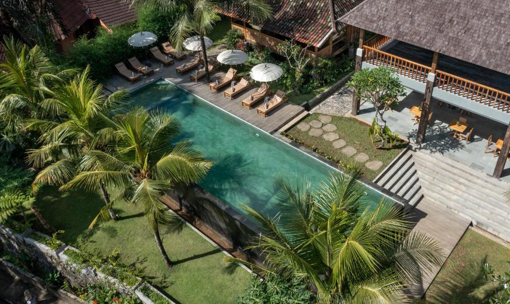 an overhead view of a swimming pool with palm trees at RUMAH KAYU RESORT in Ubud