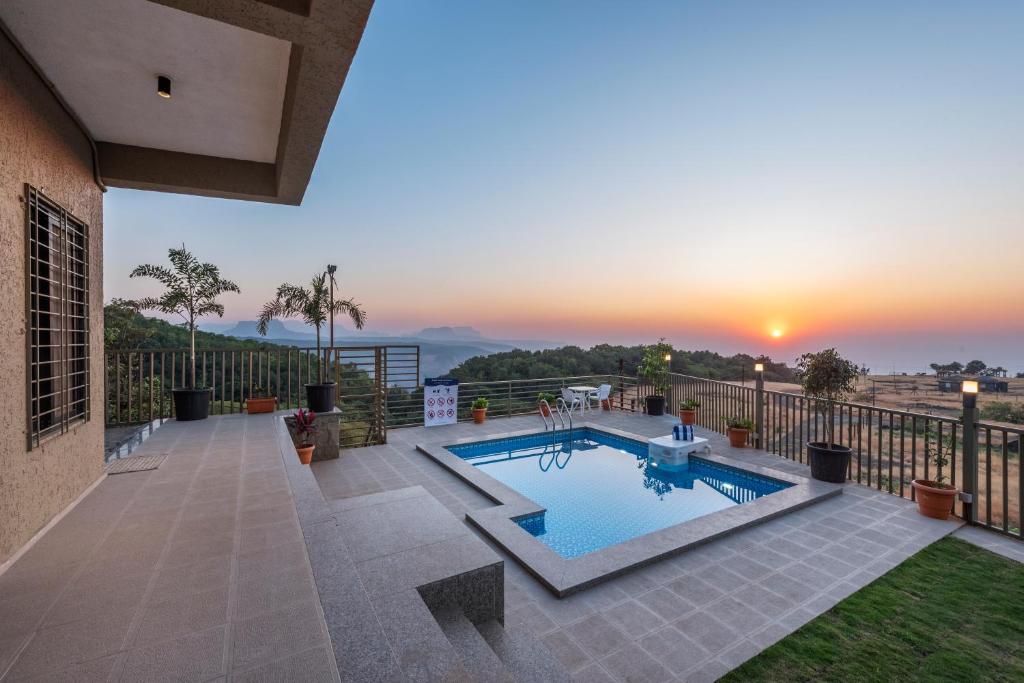 une piscine sur un balcon avec vue sur le coucher de soleil en arrière-plan dans l'établissement SaffronStays HeavOne Penta, Lonavala, à Lonavala