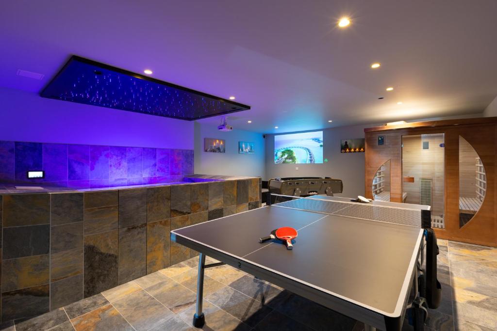 stół do ping ponga w pokoju z fioletowym oświetleniem w obiekcie Gites Spa Strasbourg - Villa Lion - SPA Privé, Sauna, Borne d'arcade, Babyfoot w mieście Ittenheim