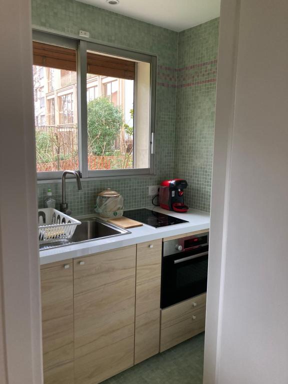 uma cozinha com um lavatório e uma janela em Vue sur jardin, 3 pièces em Paris